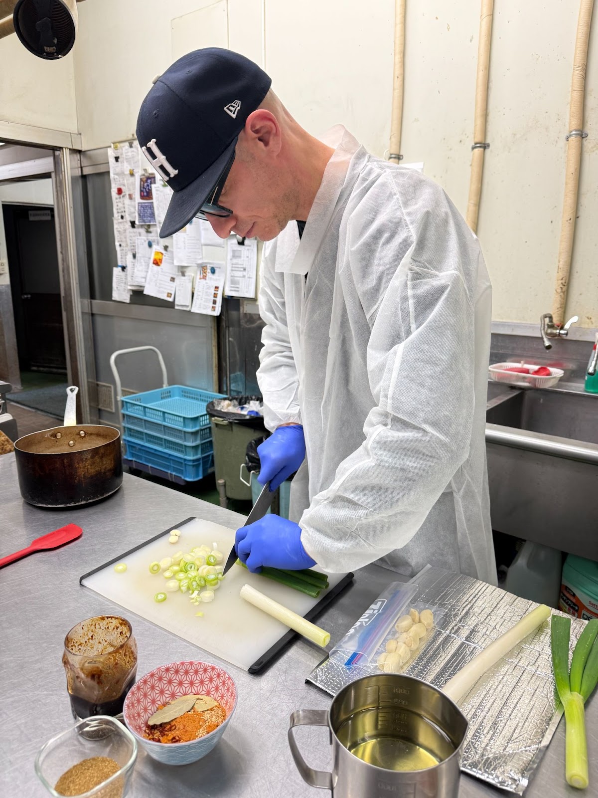 Founder of Azabu Foods preparing Umami Everything in a kitchen slicing Negi (Japanese Leak)